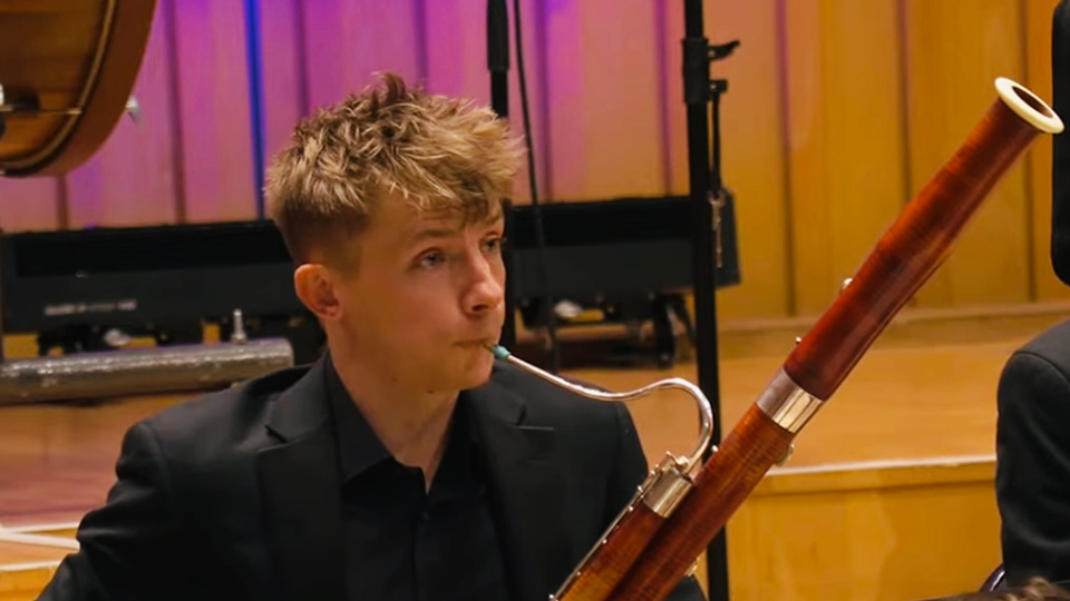 William Kidner - A male student wearing a black shirt, playing on a bassoon in a performance.